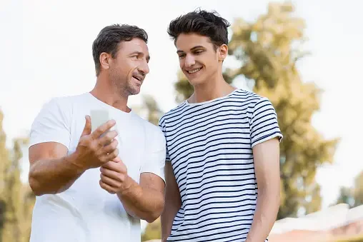 Father and son looking at phone - What is OnlyFans and Why Is It So Dangerous