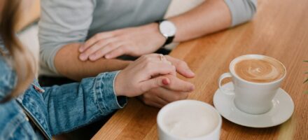 Couple sharing a coffee holding hands, trust and accountability